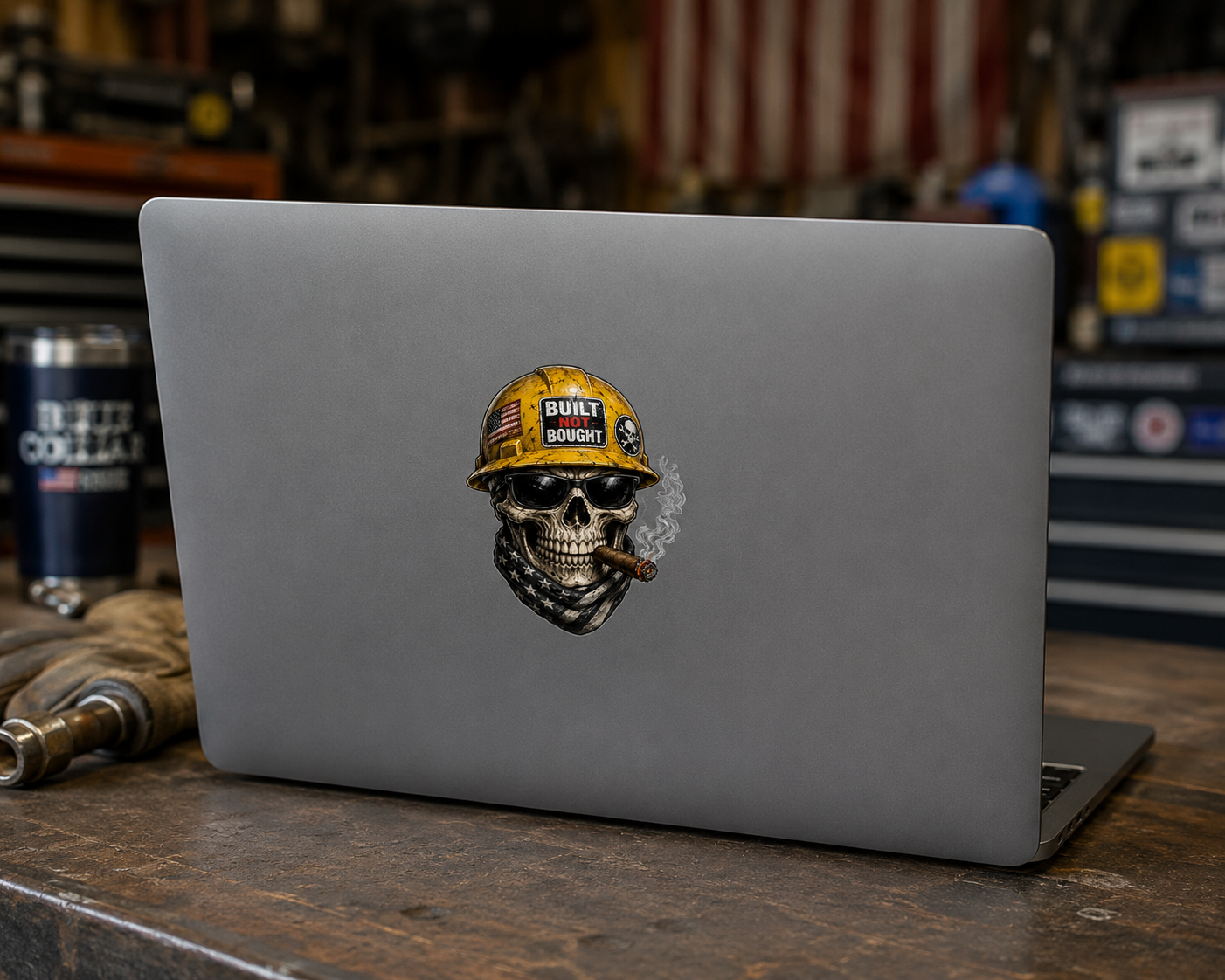 Laptop with a skull wearing a hard hat sticker on a wooden surface.